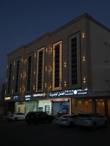 a building with cars parked in a parking lot at شقق أونيسن للشقق المخدومة Onsen Serviced Apartments in Buraydah