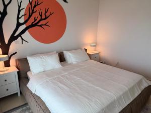 a bedroom with a bed with a tree mural on the wall at Al Raha Beach modern 1 bedroom near AD airport in Abu Dhabi