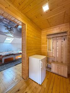 a kitchen with a white refrigerator in a wooden room at Під соснами in Krivorovnya