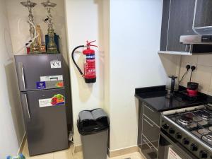 a kitchen with a refrigerator and a trash can at Al Raha Beach modern 1 bedroom near AD airport in Abu Dhabi