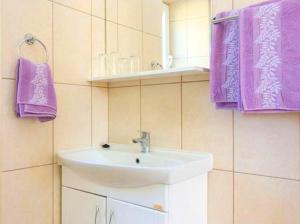 a bathroom with a sink and purple towels at Sandy Beach Apartments in Koločep