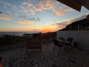 a patio with a table and chairs and the sunset at Olive tree villa in Ligia