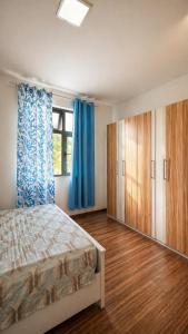 a bedroom with a bed and blue curtains and a window at Zenith Apartment in Baie du Tombeau +18 photos