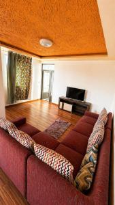 a living room with a red couch and a television at Zenith Apartment in Baie du Tombeau