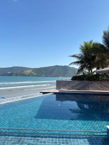 a swimming pool next to a beach with palm trees at Kaliman Pousada in Ubatuba +280 photos