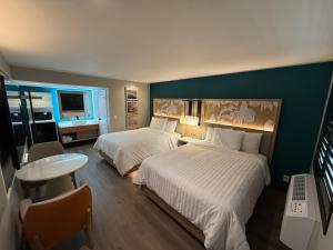 a hotel room with two beds and a table at Harbor Bay Inn in Costa Mesa