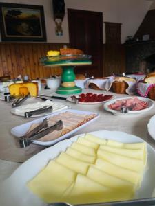 a table with cheese and plates of food on it at Pousada Dona Elza in Monte Verde +16 photos