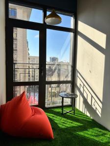 a room with a large window with a red pillow and a table at Smile Residence Bishkek in Bishkek