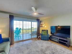 a living room with a flat screen tv and a balcony at Sandcastle Townhomes #24 in Navarre