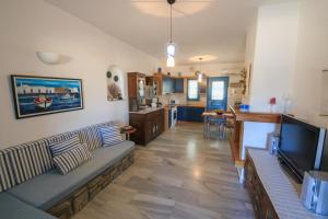 a living room with a couch and a tv and a kitchen at Anemos in Drios