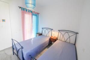 two twin beds in a room with a window at Anemos in Drios
