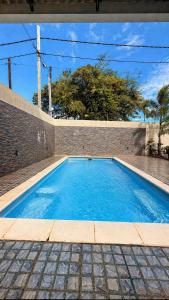 a blue swimming pool next to a brick wall at Zenith Apartment in Baie du Tombeau