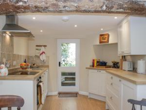 a kitchen with white cabinets and a window at Upper Frogpool Cottage in Crediton
