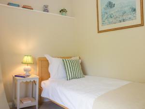 a bedroom with a bed and a side table with a lamp at Upper Frogpool Cottage in Crediton