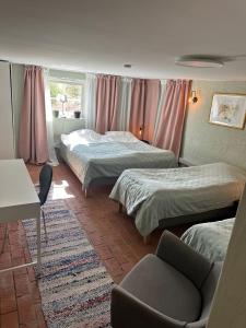 a hotel room with two beds and a chair at Lägenhet Övergran in Bålsta