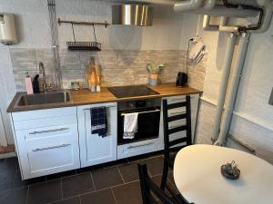a kitchen with white cabinets and a sink and a table at Lägenhet Övergran in Bålsta