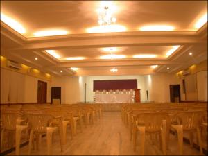 Habitación grande con hileras de sillas y un escenario en Hotel Saradharam en Chidambaram