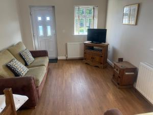 a living room with a couch and a television at Pinfold Holiday Cottage in Laxey