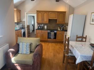 a kitchen with a couch and a table and a refrigerator at Pinfold Holiday Cottage in Laxey