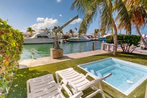 two chairs and a swimming pool with a boat in the water at KC28 Fantastic Fifth Street in Key Colony Beach