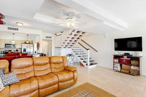 a living room with a leather couch and a staircase at KC28 Fantastic Fifth Street in Key Colony Beach
