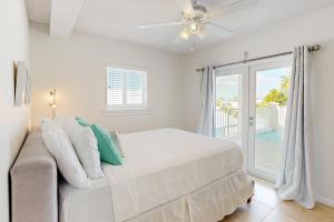 a white bedroom with a bed and a sliding glass door at KC28 Fantastic Fifth Street in Key Colony Beach