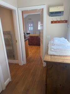 a room with a hallway with a table with towels on it at Pinfold Holiday Cottage in Laxey