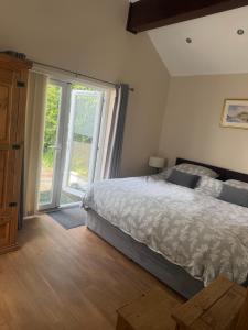 a bedroom with a bed and a large window at Pinfold Holiday Cottage in Laxey
