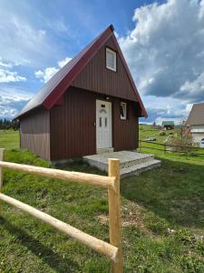a barn with a white door and a wooden fence at Cottage Martina in Žabljak