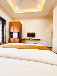 a bedroom with a large bed and a tv at Shree Gurukripa Inn in Maheshwar