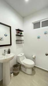 a white bathroom with a toilet and a sink at Almarena Mazatlan Departamento Nautico in Mazatlán