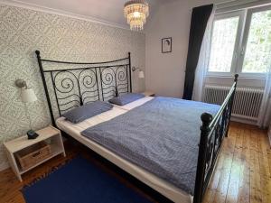 a bedroom with a black bed with blue sheets and a chandelier at Sommerhaus Luisa in Vimmerby