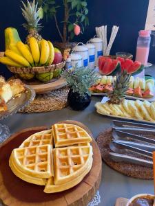 a table topped with waffles and fruit on plates at Morada do Estaleiro in Balneário Camboriú
