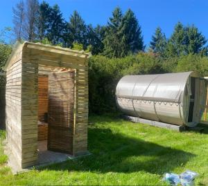 ein kleiner Holzschuppen im Gras neben einem Gebäude in der Unterkunft Le tonneau in Sivry