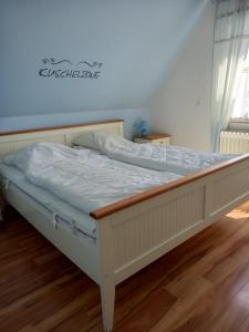 a white bed in a room with a wooden floor at Ferienwohnung Kreider in Dagebüll
