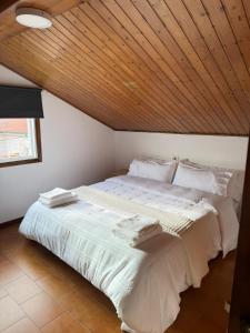 a large white bed in a room with a wooden ceiling at Casa do Carballo in Nigrán