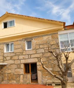 a stone house with a tree in front of it at Casa do Carballo in Nigrán