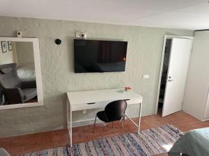a room with a desk and a television on a wall at Lägenhet Övergran in Bålsta