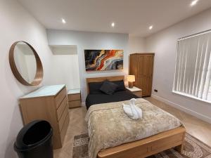 a bedroom with a bed with a white swan on it at Hendham Rooms - Near Etihad Stadium, CoOp Live Arena, National Cycling Centre & 24 Hour Asda in Manchester
