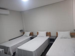 two beds in a room with white walls at Hotel Parada KM364 in Santo Antonio do Rio Abaixo