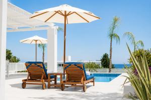 two chairs and a table with an umbrella next to a pool at Villa Mytikas in Gennadi