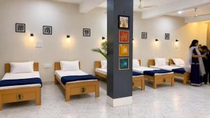 a group of beds in a room with people standing around at Rahat Dormitory in Jāmb +12 photos