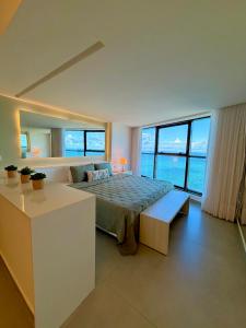 a bedroom with a bed and a desk with windows at Refuge Beira Mar - Boa Viagem in Recife