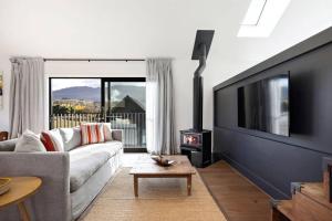 a living room with a couch and a tv and a fireplace at Luxury Mountain View Retreat in Frankton
