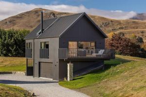 a black house with a balcony on a hill at Luxury Mountain View Retreat in Frankton