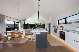 a kitchen with white counters and a table and some windows at Luxury Mountain View Retreat in Frankton +10 photos