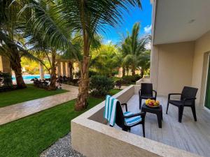 a patio with two chairs and a table and palm trees at Playa Palmera Beach Resort in Punta Cana