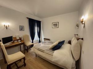 a bedroom with a bed and a desk with a computer at Ancien hôtel du Thaurion in Saint-Hilaire-le-Château +13 photos