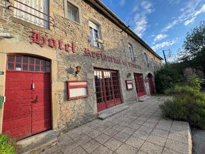 an old brick building with red doors on it at Ancien hôtel du Thaurion in Saint-Hilaire-le-Château