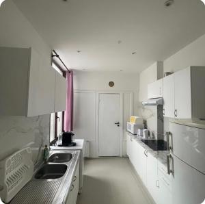 a small kitchen with white cabinets and a pink curtain at Grace Family Home 2 in Brussels